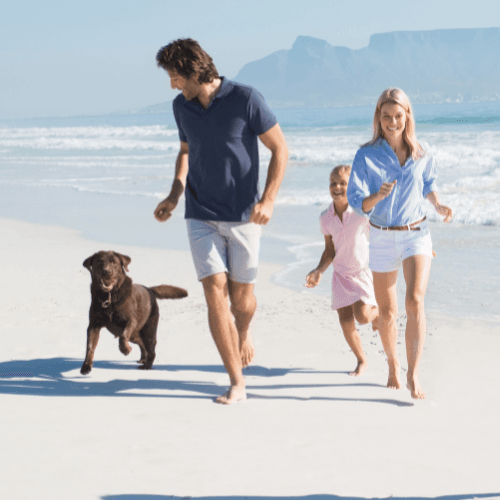 Family running with a dog off leash on a beach